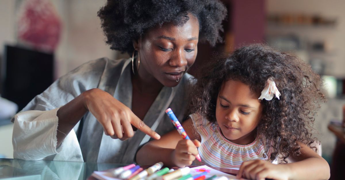 A mother and daughter enjoy quality time coloring together indoors.