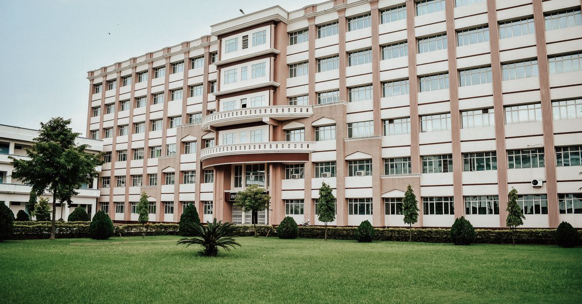 A large modern multi-story building with a well-maintained green lawn.